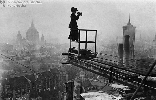 A Female Reportage Photographer Surveys Berlin (c. 1910) Women in journalistic professions were a rarity in Wilhelmine Germany. Nonetheless, some women did succeed in establishing themselves as journalists – initially, they did so by working for the women&rsquo;s newspapers and magazines that had been around since the middle of the nineteenth century; later on, they also worked for large newspapers. In this photograph (c. 1910), a female photographer surveys metropolitan Berlin from a crane being used in the construction of the Stadthaus [City Hall] on Molkenmarkt. The City Hall was built as an extension of the Rotes Rathaus [Red City Hall], whose large tower can be seen at the right. The Berliner Dom [Berlin Cathedral] can be seen in the background off to the left.<br /><br /><br />
via GHDI 