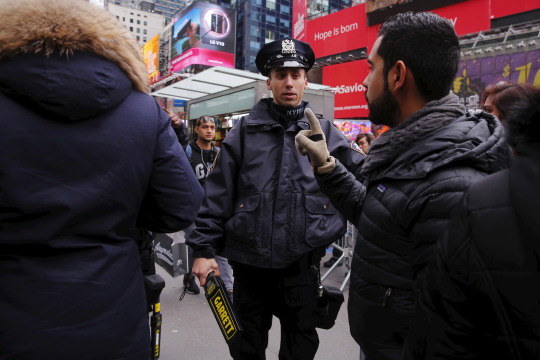 A New York Police Department officer speaks with revelers as they wait for the beginning of New Year's Eve festivities in the Times Square area of New York December 31, 2015. REUTERS/Lucas Jackson